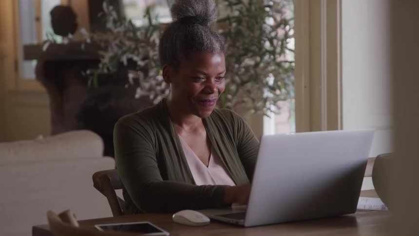 Woman sitting at a table typing on laptop