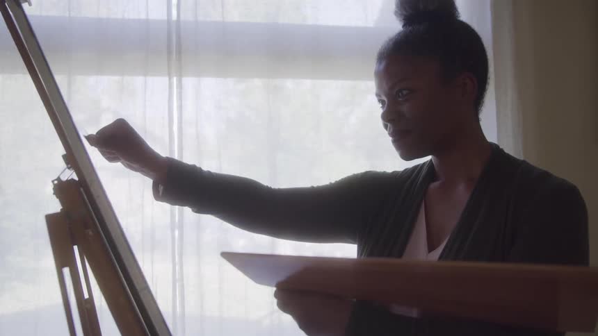 Woman with happy expression painting a canvas