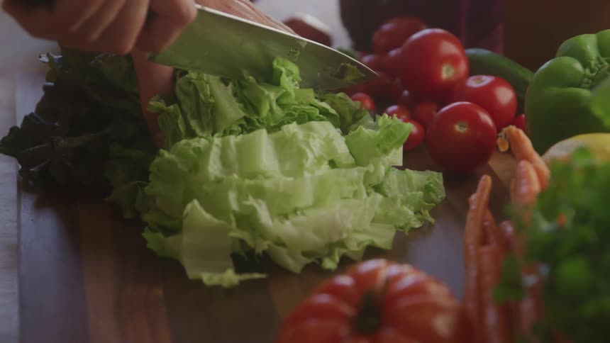 Person with a knife chopping salad on a cutting board