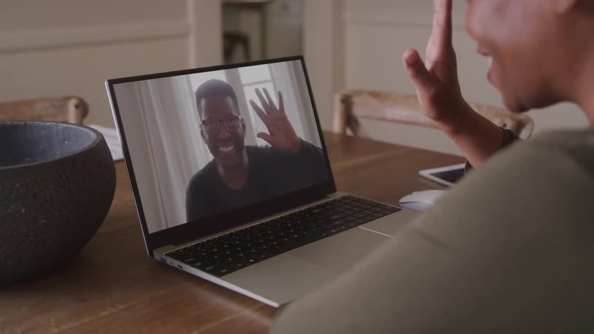 A joyful couple share a video call and wave at each other