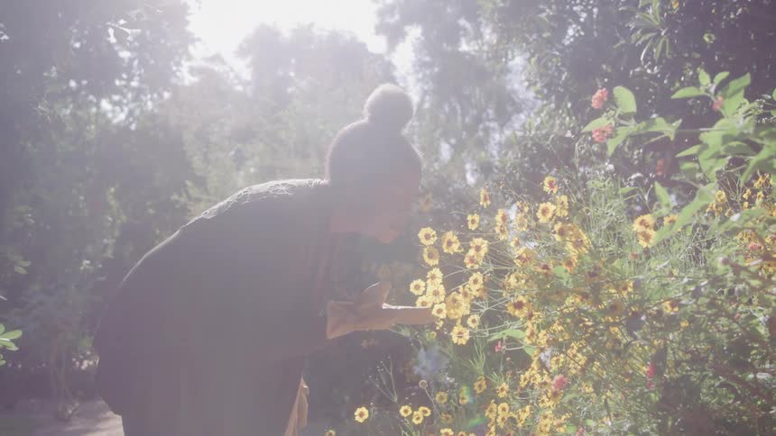 Woman smelling yellow flowers in the forest
