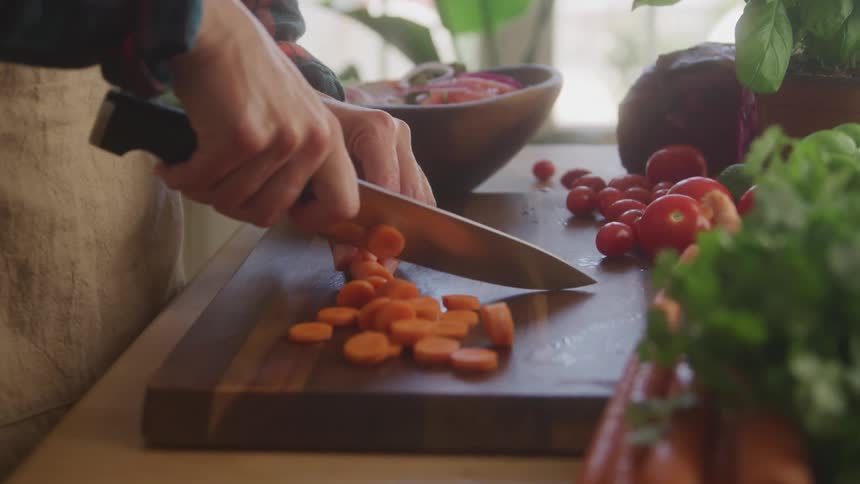 Person chopping carrots with a knife on a cutting board