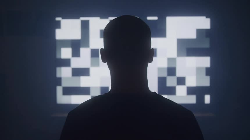 A silhouetted adult male stands with his back to the viewer facing a large screen displaying a white and grey pixelated abstract pattern that flickers and shifts