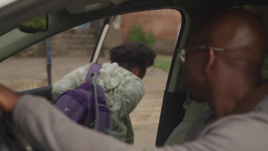 A father dropped his daughter at school she hopped out of the passenger seat opened and closed the door waved to her father and walked toward the school