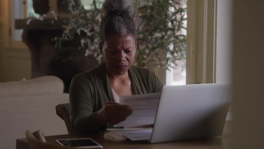 Woman sitting at a table with laptop open reading a document