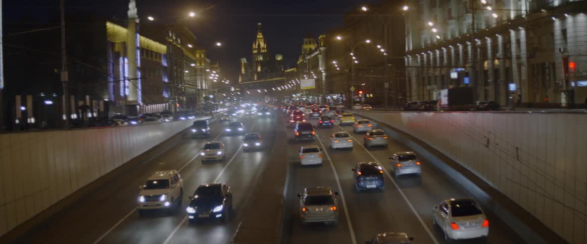Cars travel on roadways through a busy city at night