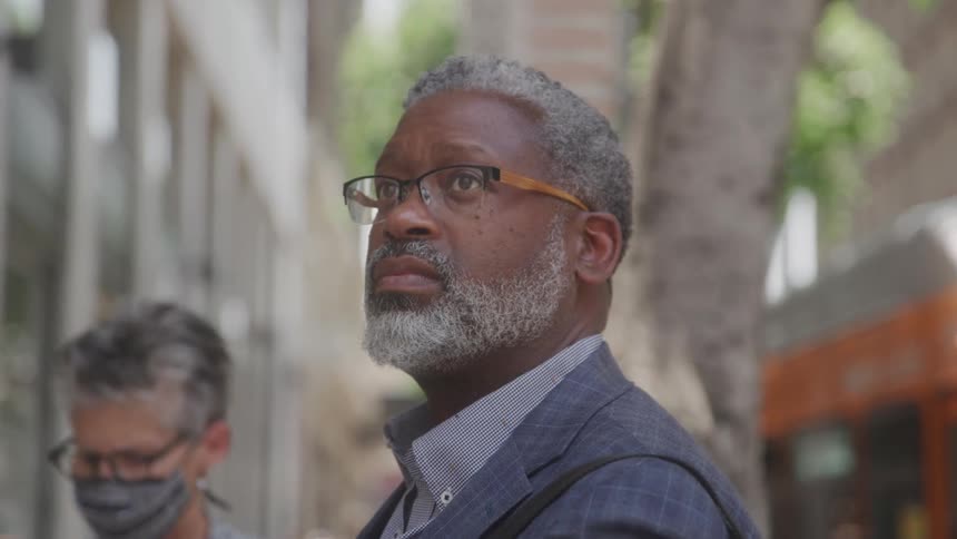 Close up portrait of a middle aged black businessman standing outdoors on a walkway during daytime