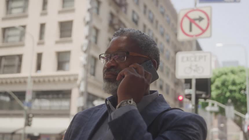 Man in suit outdoors in city talking on cell phone