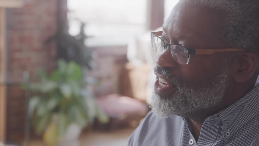 Man with glasses and beard in an indoor space talking