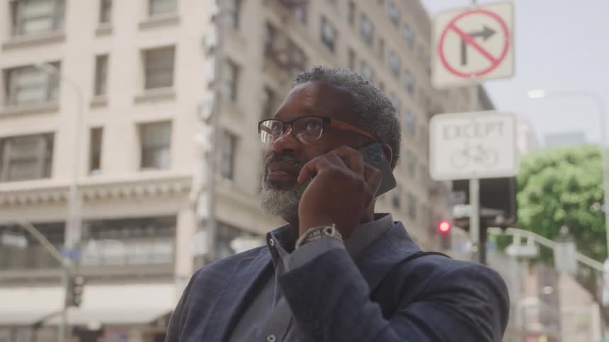 Man in glasses outdoors talking on smartphone