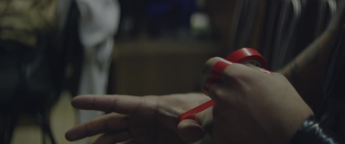 Man wraps red tape around his fingers