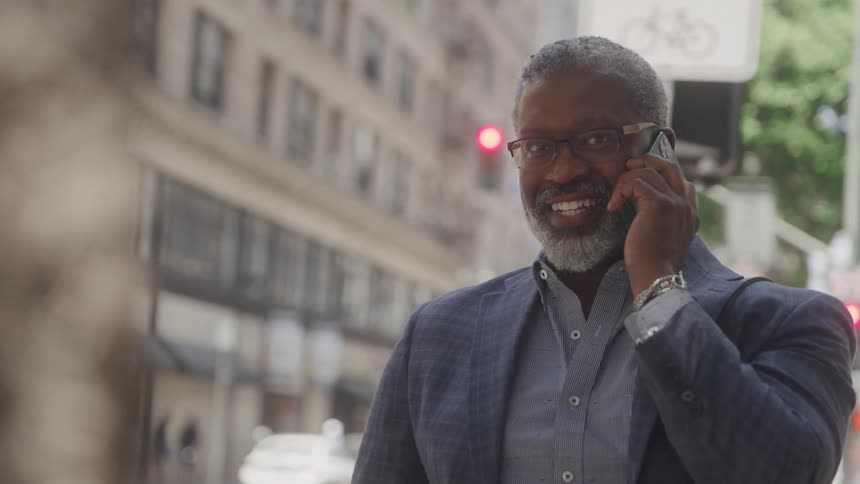Man smiling on his hone in he city