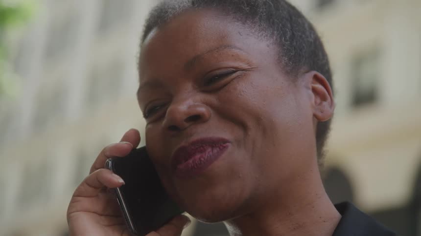 A woman smiling and laughing while having a conversation on her smartphone