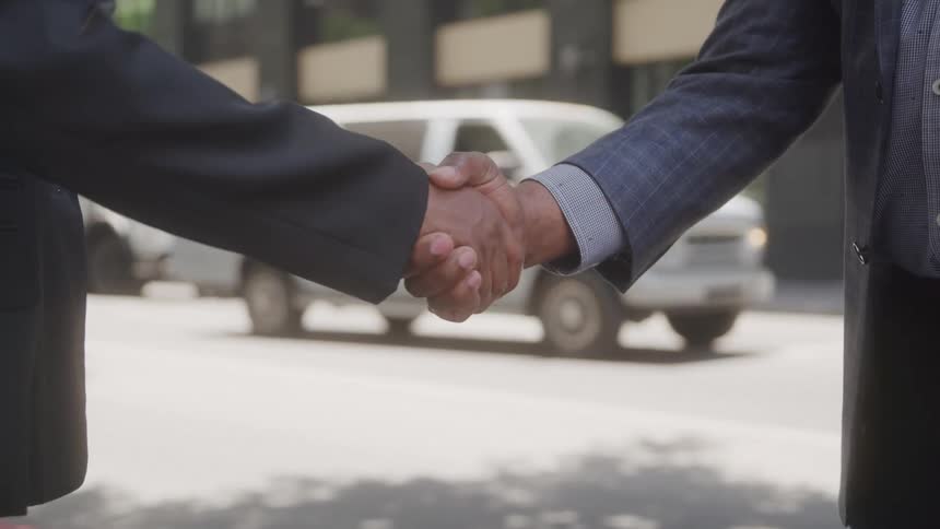 Two men shake hands in he street