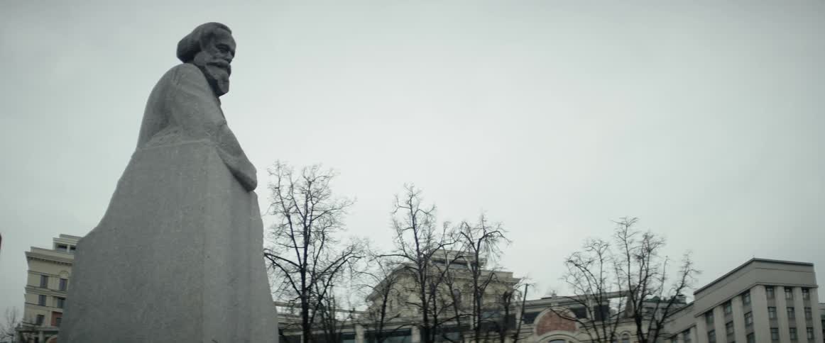 A large stone statue sits by some buildings