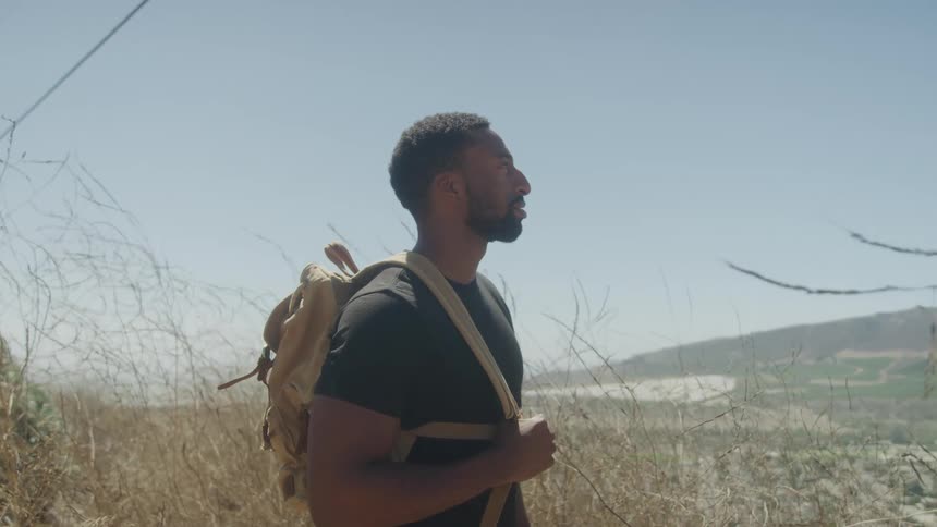 Man in a natural environment with a backpack on his back and mountains in the background