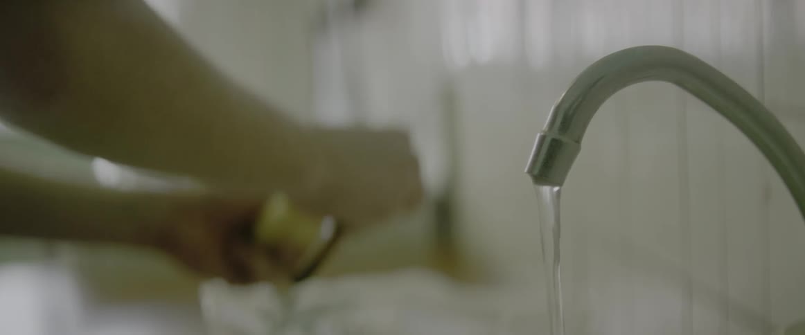 Person peeling a potato while periodically placing it under a running faucet