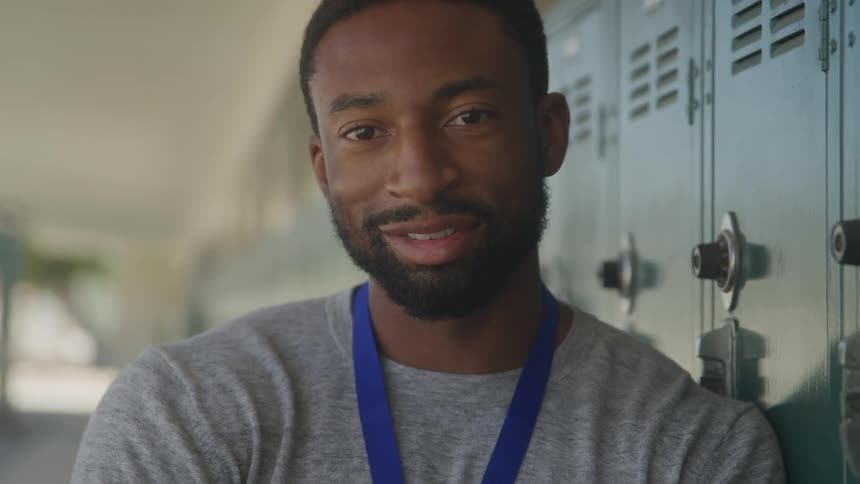 Man leaning against lockers outside turns his head to face the camera