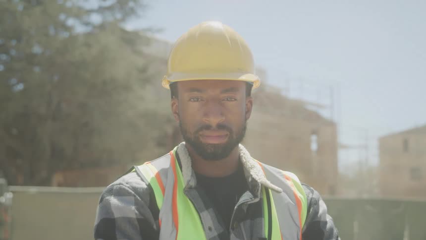 Close up male construction worker in hard hat and safety vest on construction site