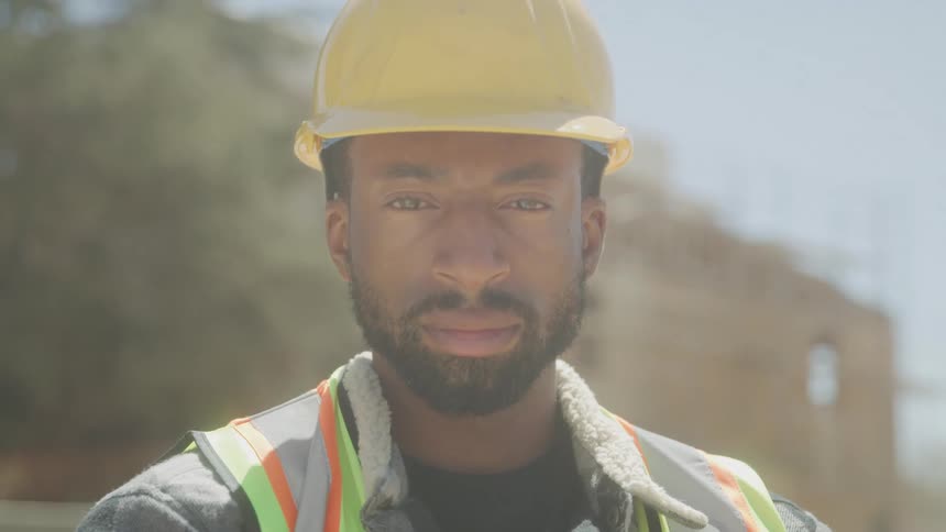 Close up male construction worker in hard hat and safety vest on construction site