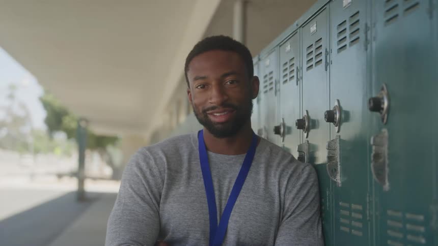 The teacher is leaning against the locker