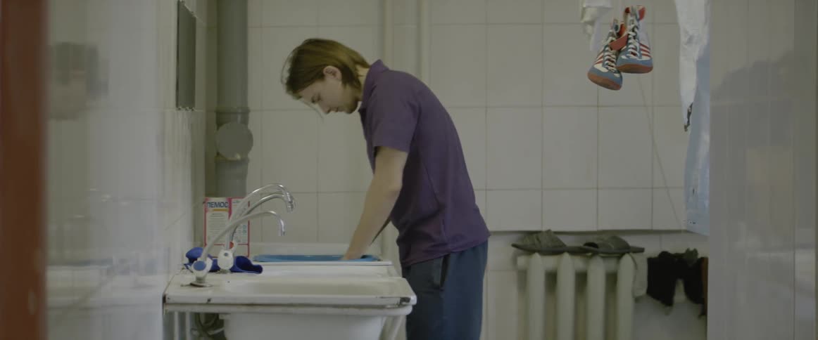 A man pouring something from a box into a sink and trying to wash them