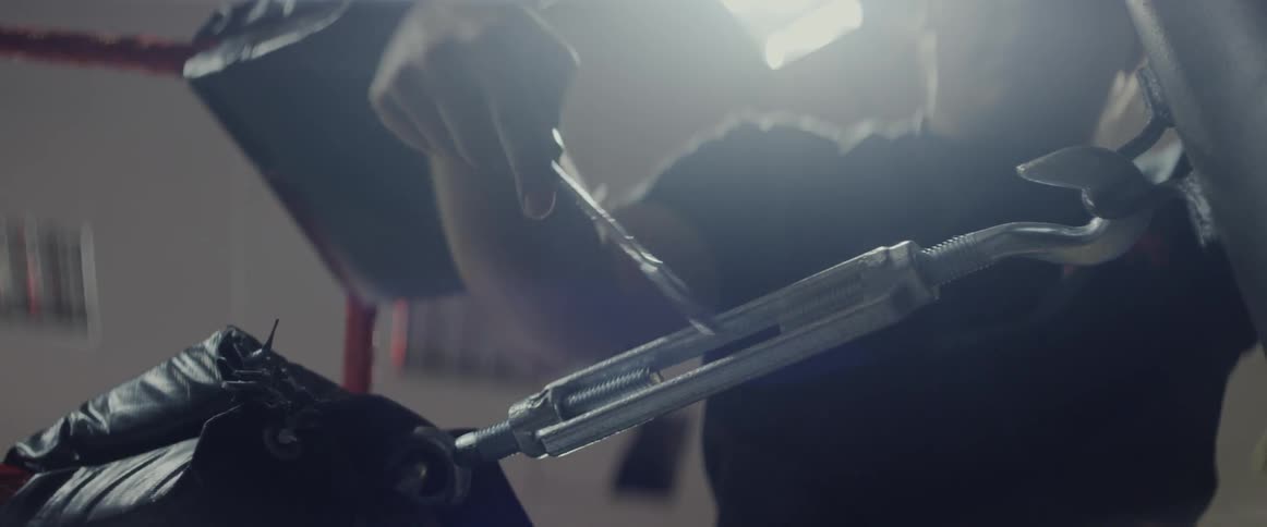 A man uses a wrench to turn a piece of metal