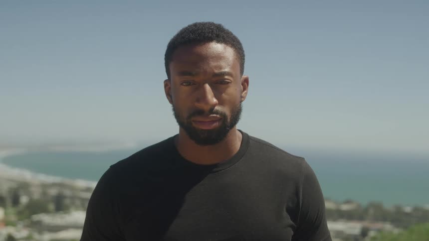 Bearded man in an outdoor setting with the sea in the background