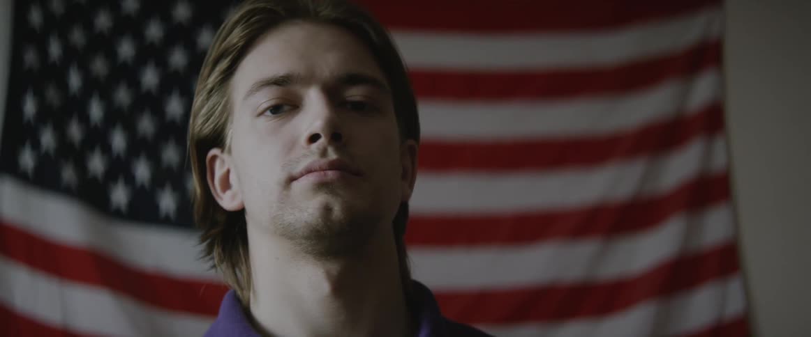 A man stands in front of an american flag