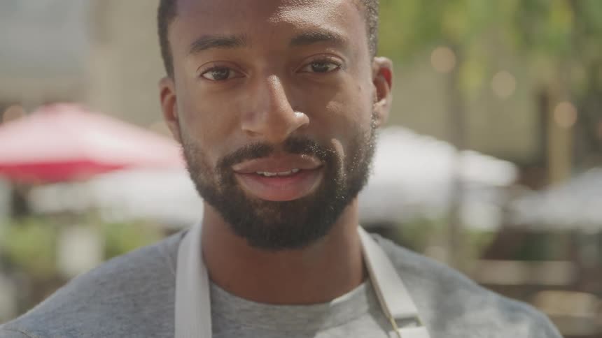 Close up portrait of a black male waiter standing outdoors during daytime