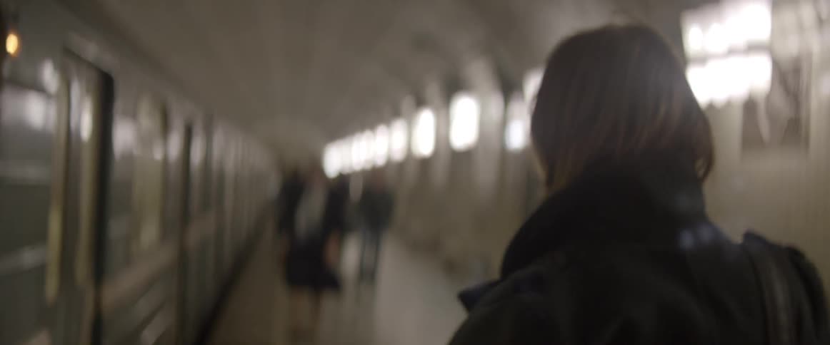 A person walking on a sidewalk waiting to board the subway