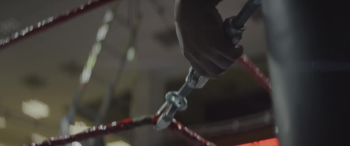 A man adjusts wrestling ring ropes
