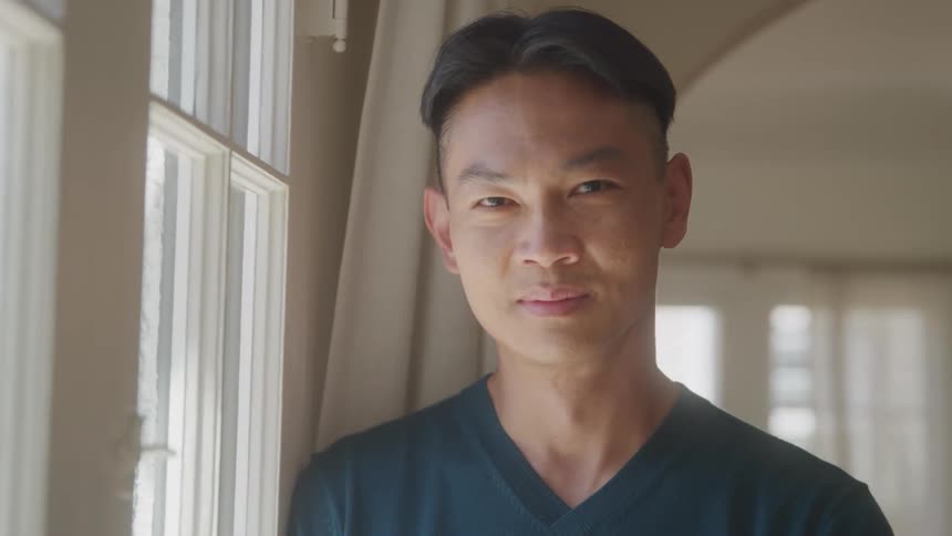 Close up asian male in black shirt standing near window indoors