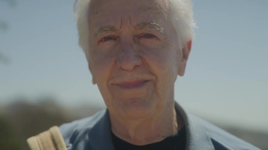 Close up portrait of an elderly man standing outdoors during daytime