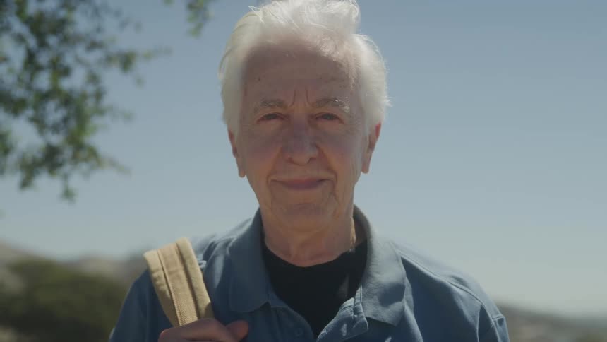 Elderly man smiling while facing the camera outdoors
