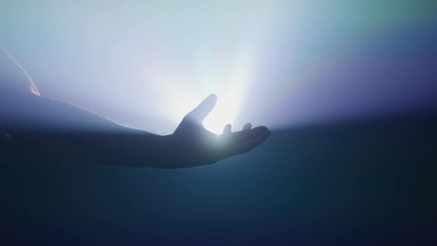 Hand closing and opening against an abstract inner light