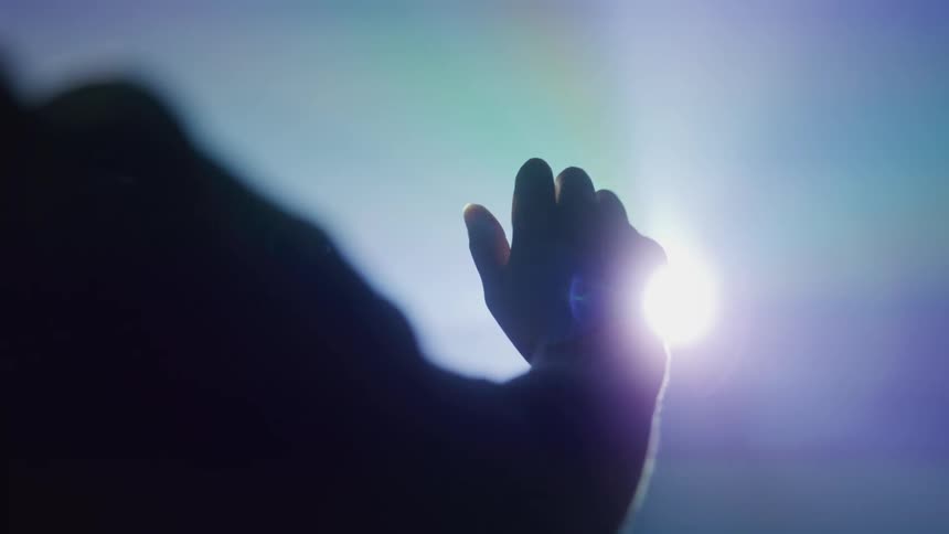Closeup of a hand opening and closing towards an abstract light