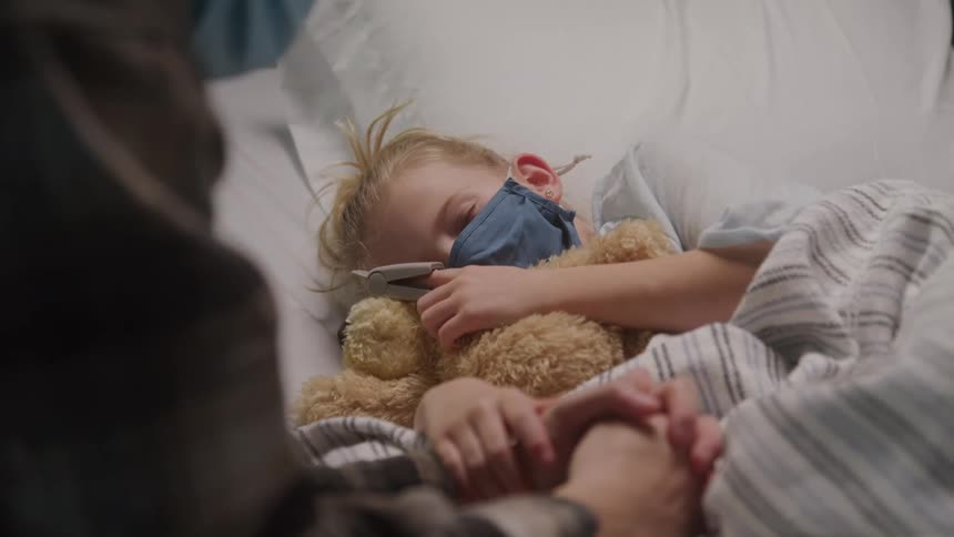 Mother sitting next to her little daughter who is sleeping in the hospital