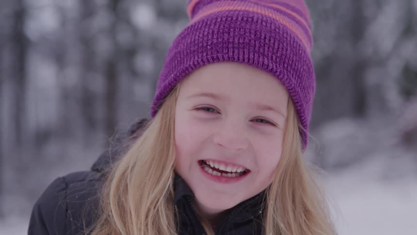 Little blonde girl outdoors in a snowy environment and smiling