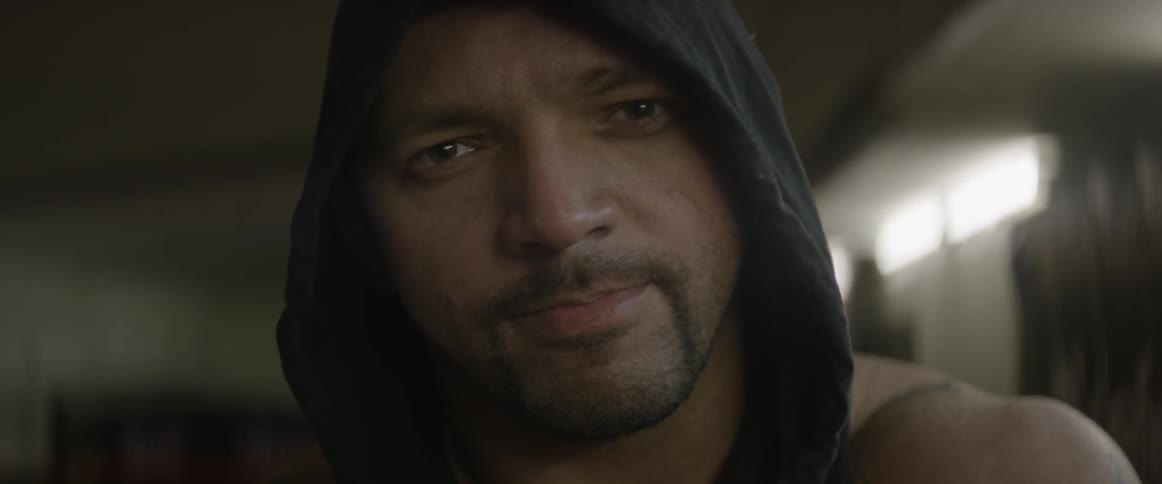 A man with a hood smiles and smirks