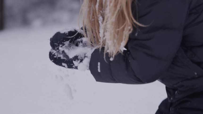Close up of a girl playing with snow outdoors during daytime