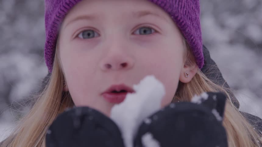 The girl blows snow from the girls gloves