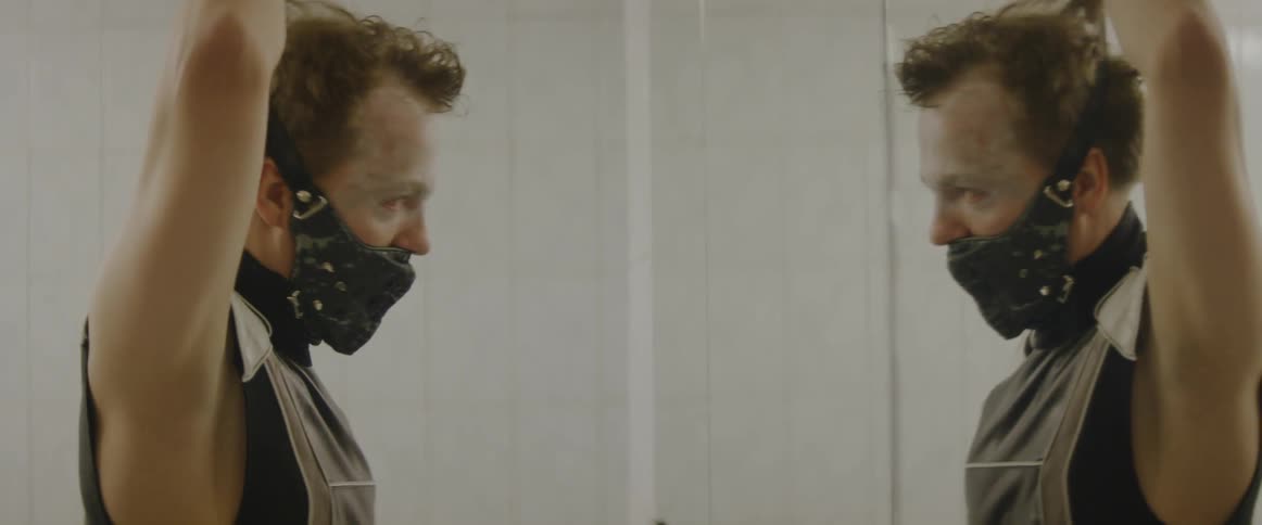 A man puts a mask on in front of a mirror