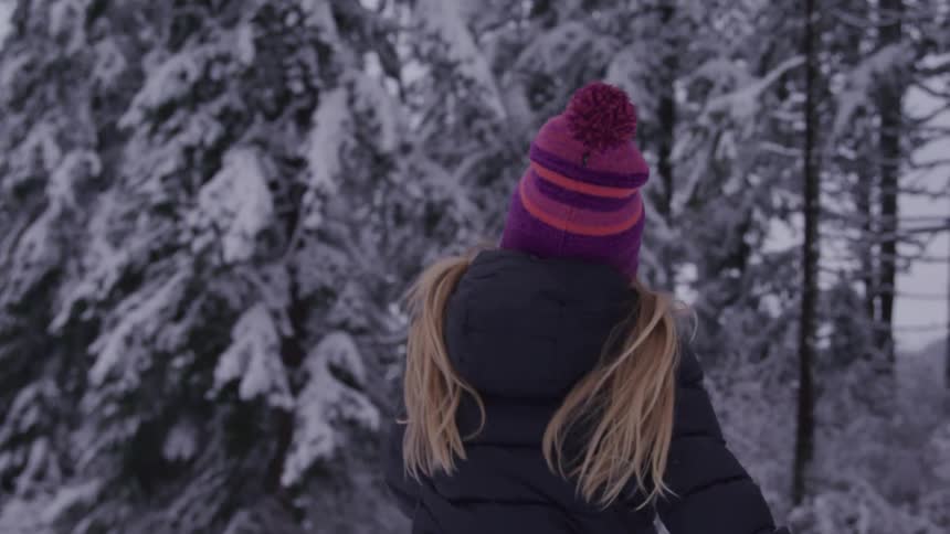 Little girl in a pink hat running in the snow