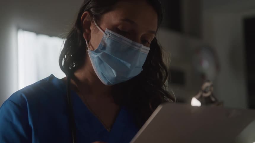 Close up of a female medical personnel taking a patients history in a hospital room during daytime