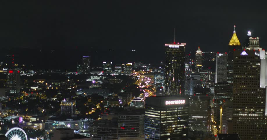 The tall buildings are brightly lit at night