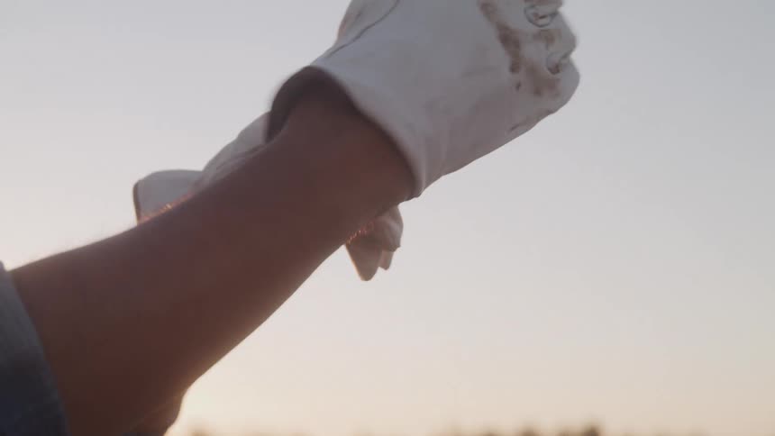 Man wearing gloves stretches his arm forward at sunset