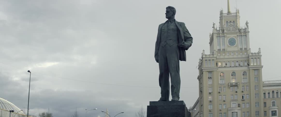 A tall statue sits in front of a building on a cloudy day