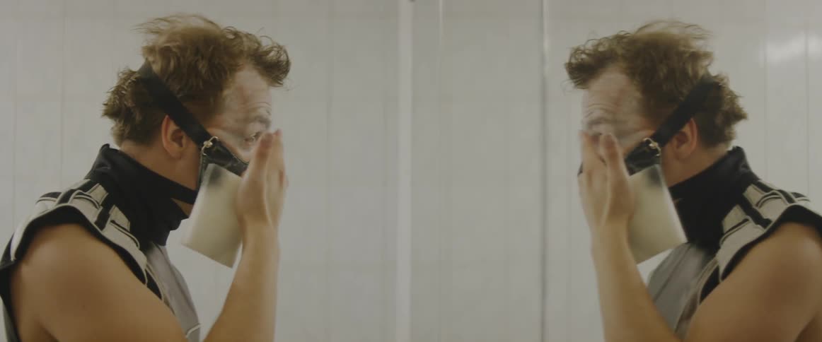 A man wearing a mask puts makeup on his face