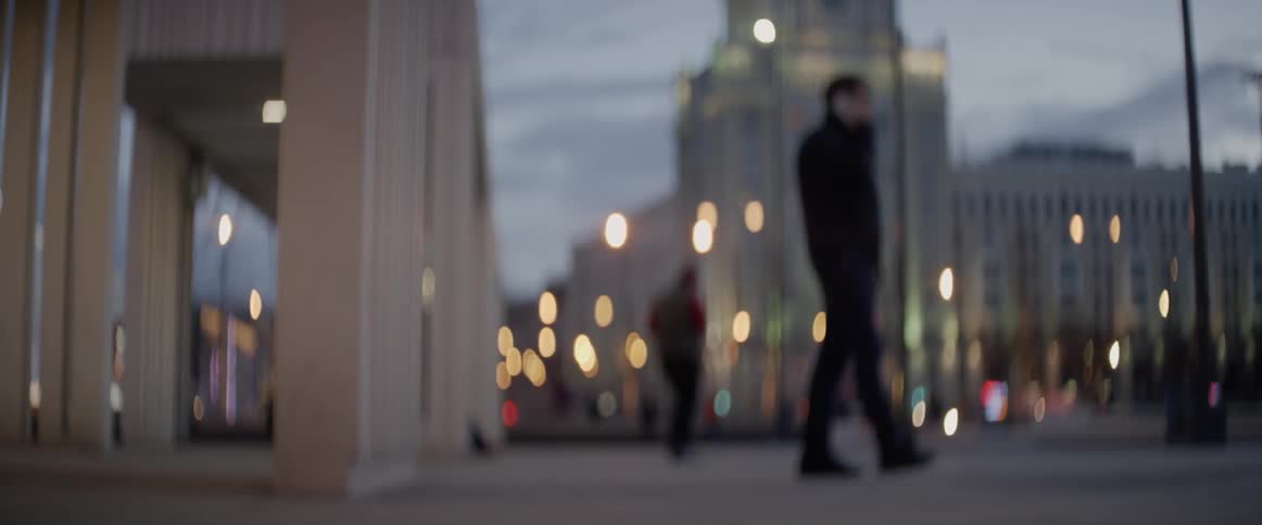 A person's legs are shown going back and forth on a swing with city buildings in the background